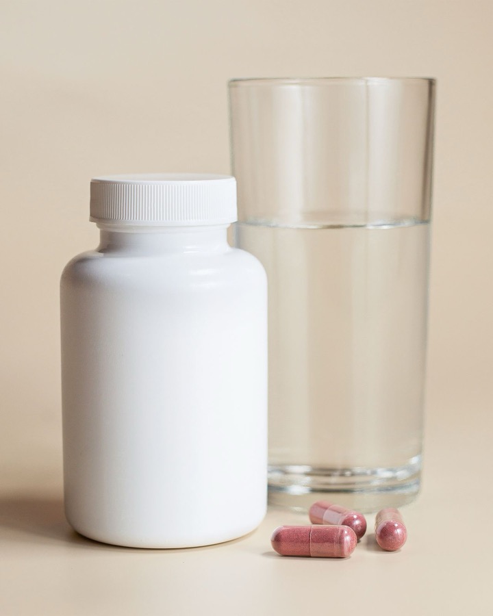 Wellness supplement bottle with capsules and a glass of water